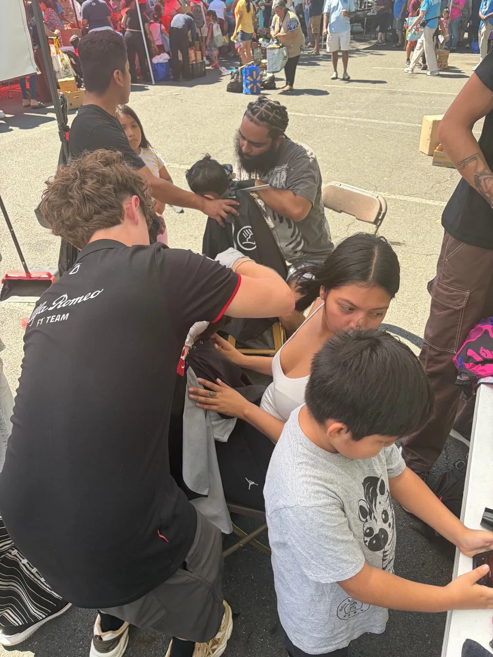 Stylists giving free haircuts to families at an outdoor community event in East Brunswick